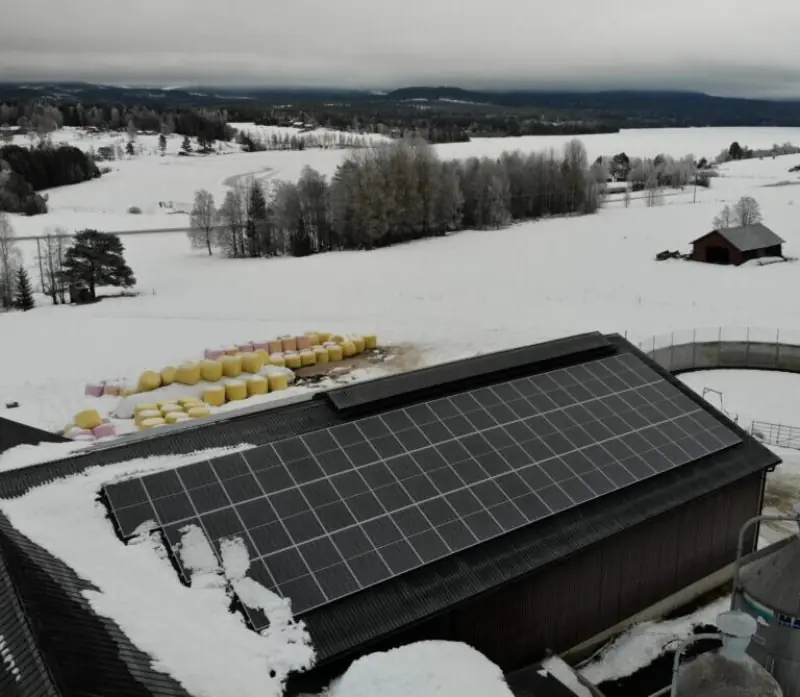 Lantbruk i Järvsö med 60 kW solcellsanläggning på ladugårdstak i vintermiljö, rundbalar i förgrunden